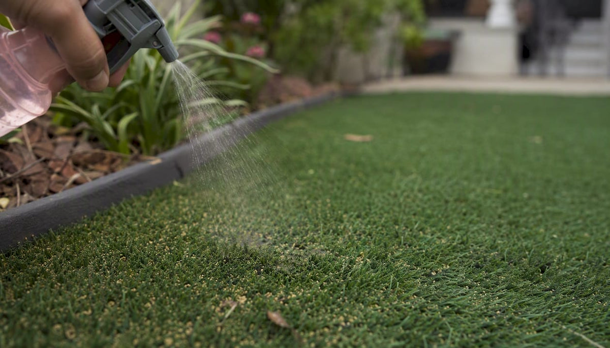 Hand pouring bleach onto artificial grass