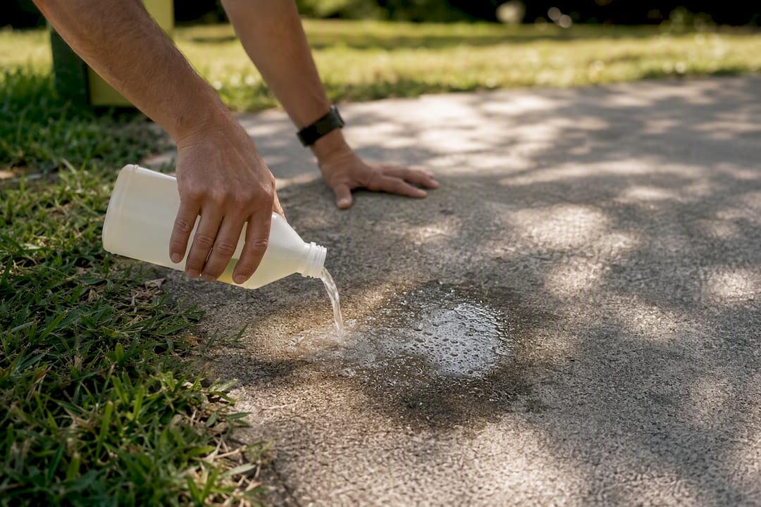 Pouring enzymatic cleaner on concrete driveway stain